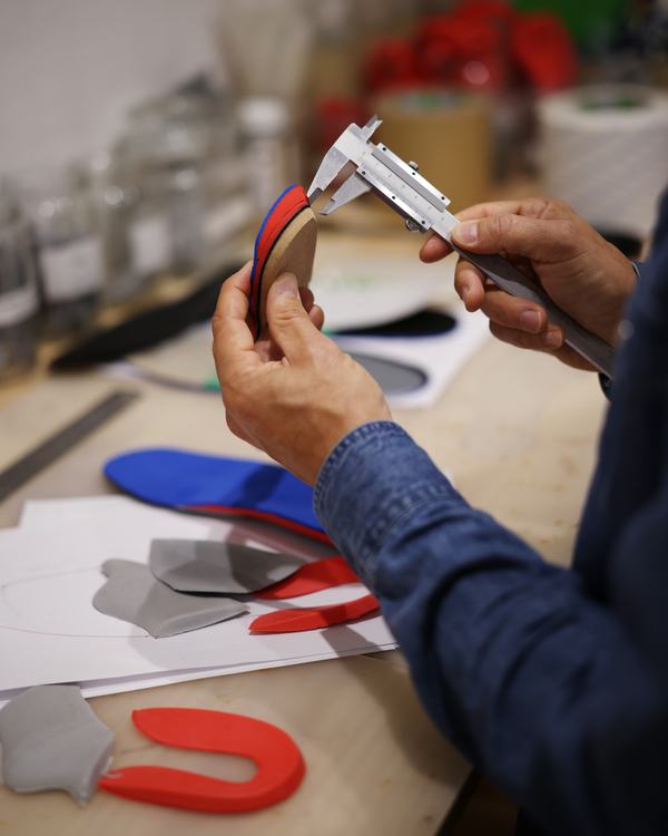 Mesure d’une semelle orthopédique au pied à coulisse sur l’établi.