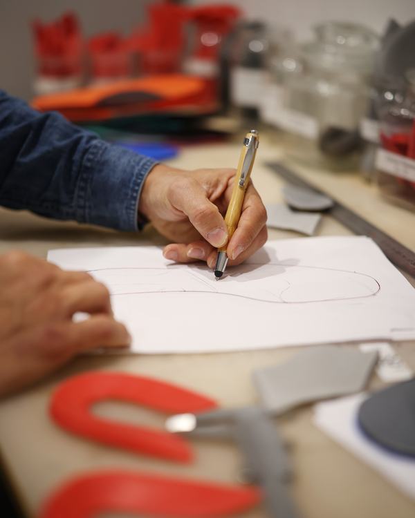 Traçage du contour d’une semelle sur papier dans l’atelier.
